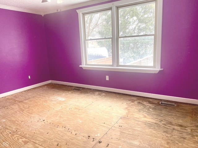 unfurnished room featuring a ceiling fan, visible vents, baseboards, and crown molding