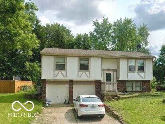 bi-level home with fence, concrete driveway, and a front yard