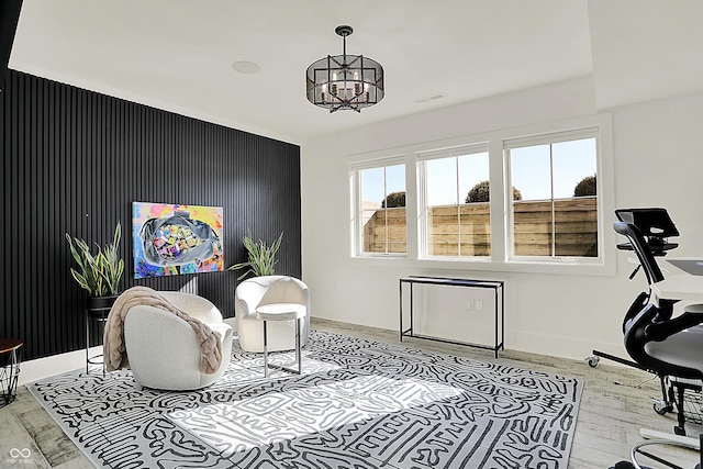 living area with baseboards, visible vents, light wood-style flooring, and an inviting chandelier