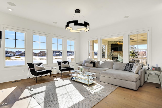 living area featuring a wealth of natural light, a fireplace, wood finished floors, and visible vents