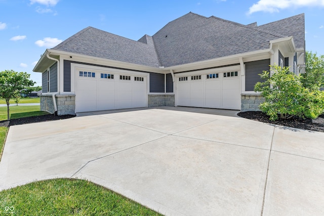 view of front facade featuring stone siding, concrete driveway, roof with shingles, and an attached garage