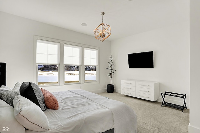 carpeted bedroom featuring a notable chandelier and baseboards