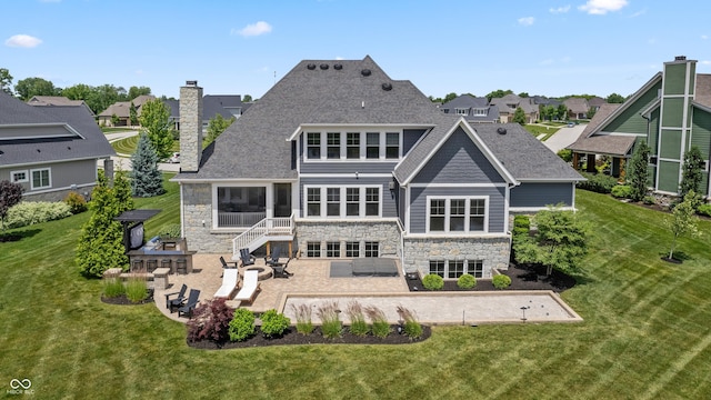 back of property featuring stone siding, a patio, a chimney, and a lawn