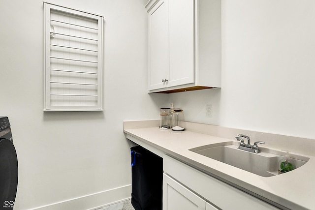 interior space featuring washer / clothes dryer, a sink, cabinet space, and baseboards