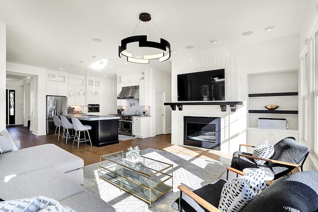 living area featuring a brick fireplace, dark wood-type flooring, and recessed lighting