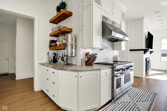 kitchen with tasteful backsplash, wood finished floors, double oven range, open shelves, and exhaust hood