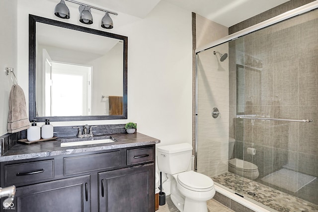 bathroom featuring toilet, a shower stall, and vanity