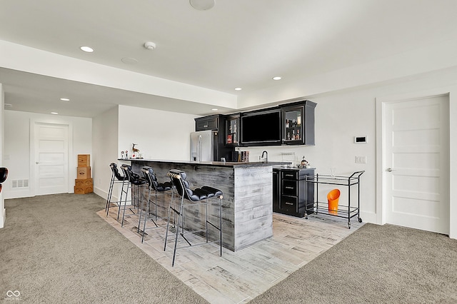 bar with recessed lighting, stainless steel fridge, wet bar, and light colored carpet