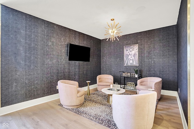 sitting room with baseboards, a chandelier, wood finished floors, and wallpapered walls