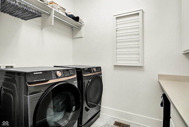 laundry area with baseboards, visible vents, and washer and clothes dryer