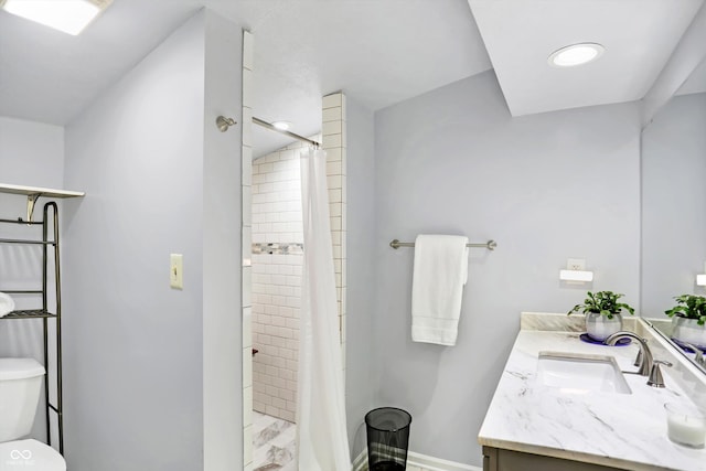 full bathroom featuring baseboards, tiled shower, vanity, and toilet