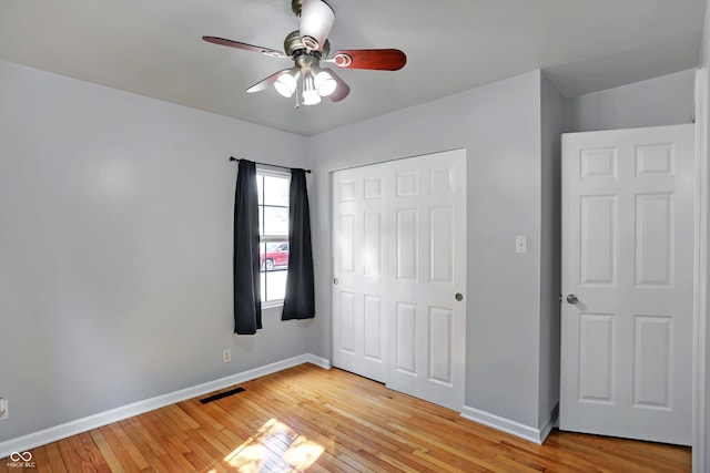 unfurnished bedroom featuring a closet, visible vents, light wood-style flooring, ceiling fan, and baseboards