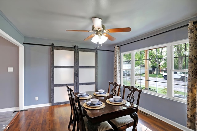 dining room featuring plenty of natural light, a barn door, visible vents, and wood finished floors