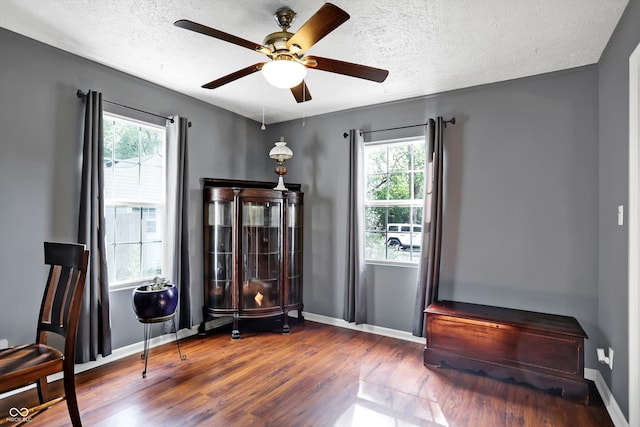 interior space with a textured ceiling, ceiling fan, wood finished floors, and baseboards