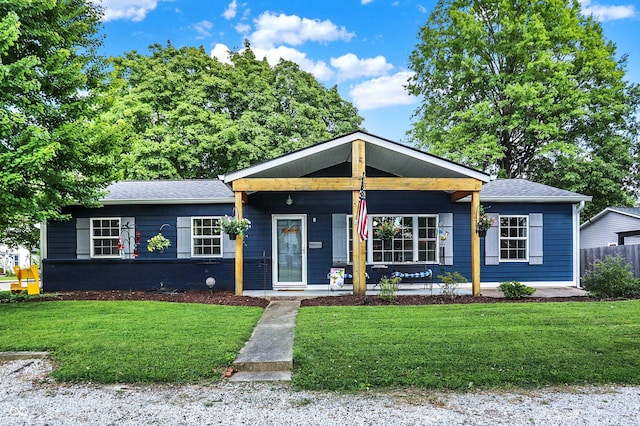 view of front of property featuring a shingled roof, a porch, a front lawn, and brick siding