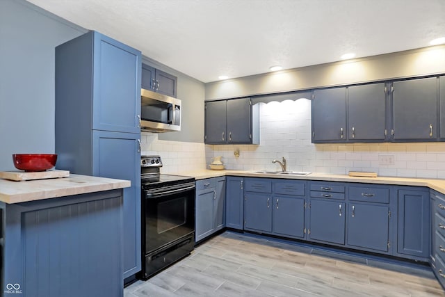 kitchen with tasteful backsplash, stainless steel microwave, black range with electric stovetop, light countertops, and a sink