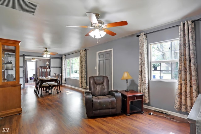 living area featuring baseboards, visible vents, ceiling fan, and wood finished floors