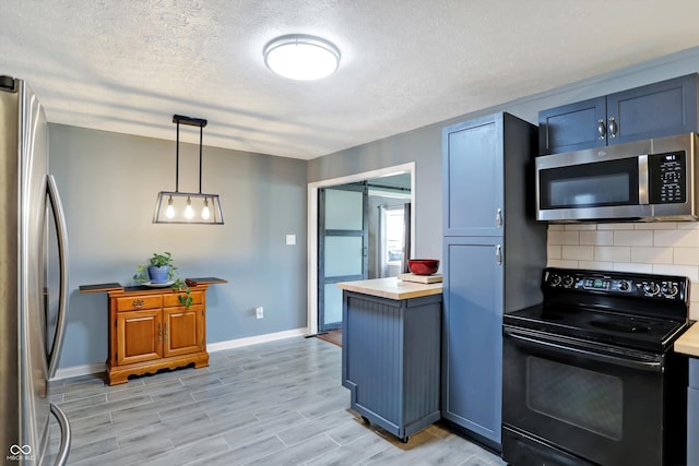 kitchen with a barn door, light wood-style flooring, appliances with stainless steel finishes, light countertops, and backsplash