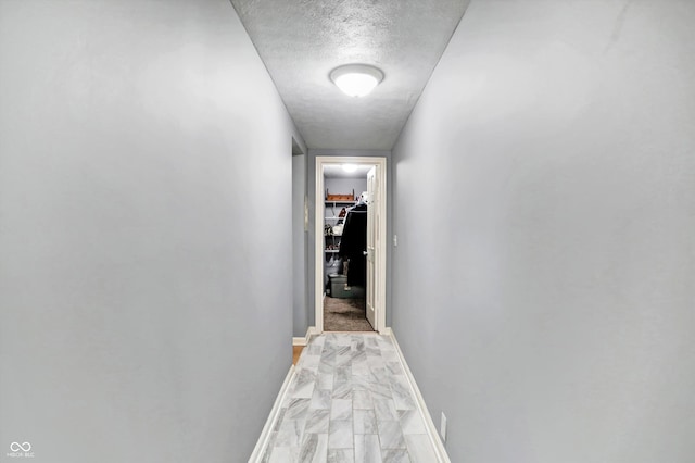 corridor with a textured ceiling and baseboards