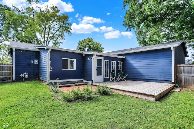 rear view of property with a deck, a yard, and fence