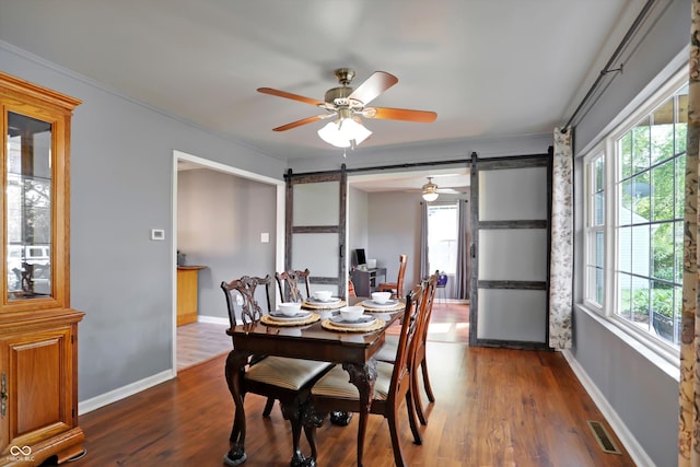 dining space featuring dark wood-style floors, a barn door, visible vents, and baseboards