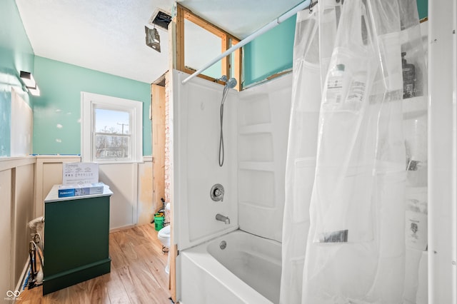 bathroom with toilet, a wainscoted wall, shower / bath combination with curtain, and wood finished floors