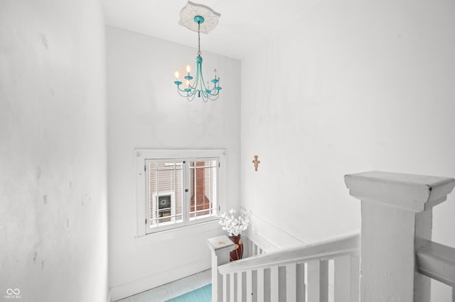 hallway with a notable chandelier and an upstairs landing