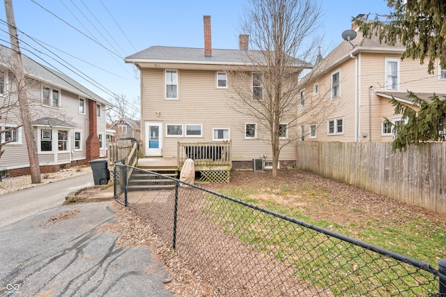 rear view of house with a deck, a fenced backyard, and a chimney