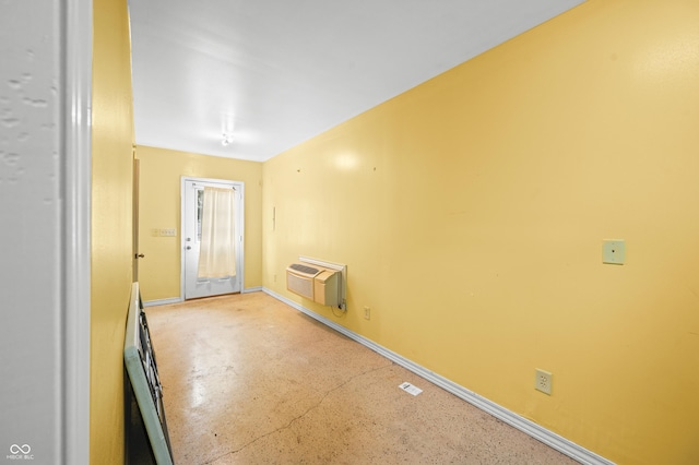 unfurnished room with a wall mounted air conditioner, concrete floors, and baseboards