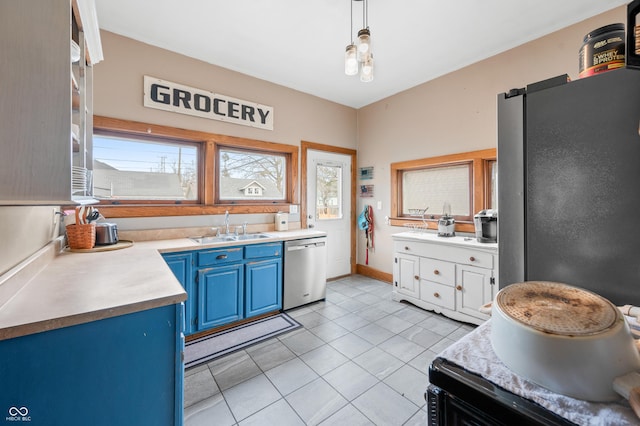 kitchen featuring light tile patterned floors, light countertops, appliances with stainless steel finishes, a sink, and blue cabinets