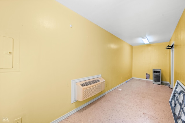 basement with baseboards, an AC wall unit, and heating unit