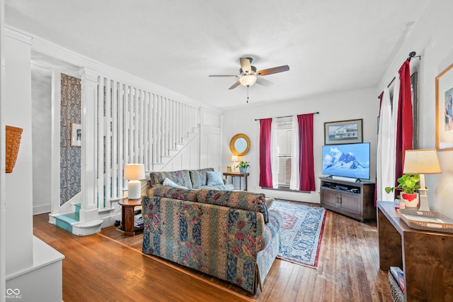 living area with a ceiling fan, hardwood / wood-style floors, and stairs