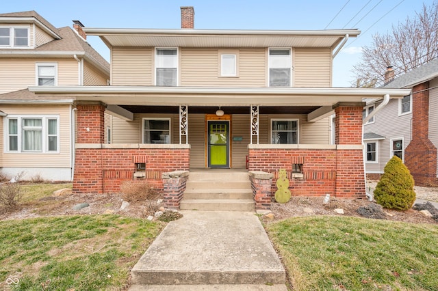 view of front of home featuring a porch, a chimney, and brick siding