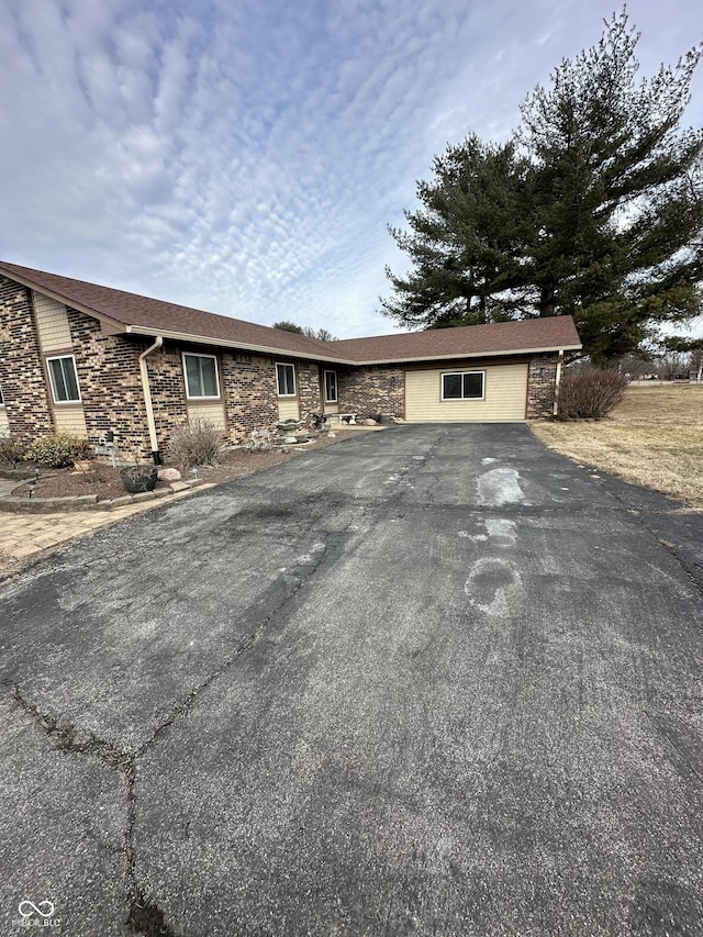 ranch-style house with aphalt driveway and stone siding