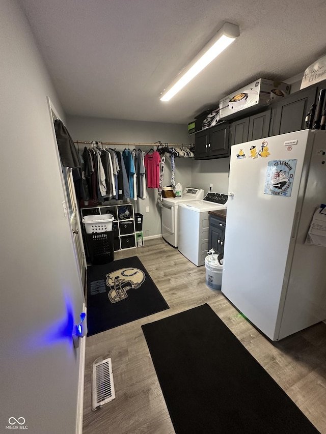 laundry room featuring cabinet space, light wood-style flooring, visible vents, and separate washer and dryer