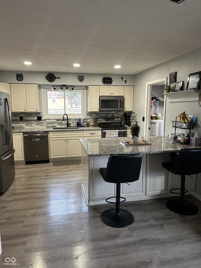 kitchen featuring stainless steel appliances, a sink, light stone counters, and a kitchen breakfast bar