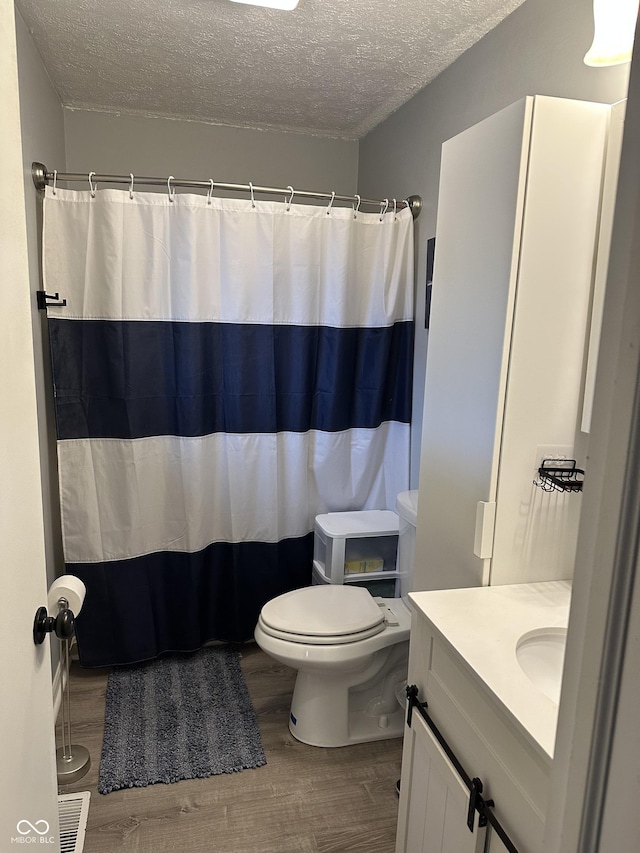 bathroom featuring a textured ceiling, visible vents, wood finished floors, and vanity