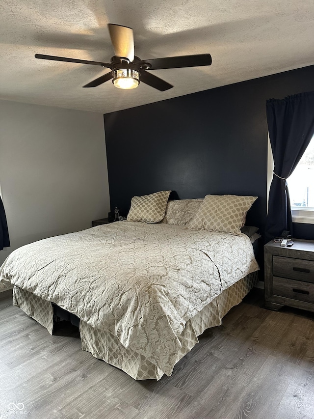 bedroom featuring a textured ceiling, a ceiling fan, and wood finished floors