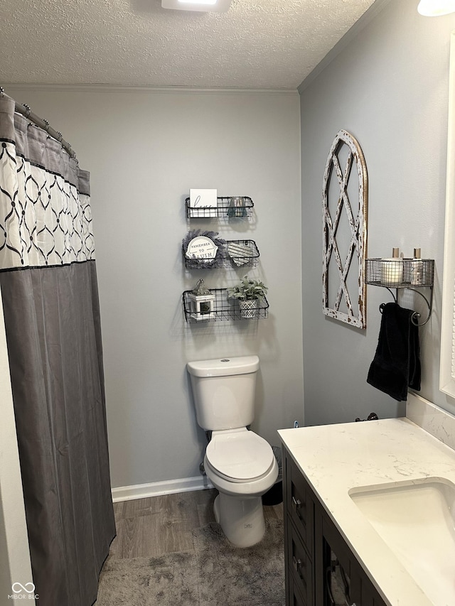 bathroom with baseboards, toilet, wood finished floors, a textured ceiling, and vanity