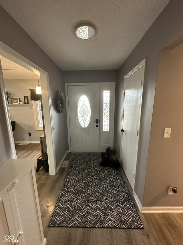 entrance foyer with a textured ceiling, baseboards, and wood finished floors