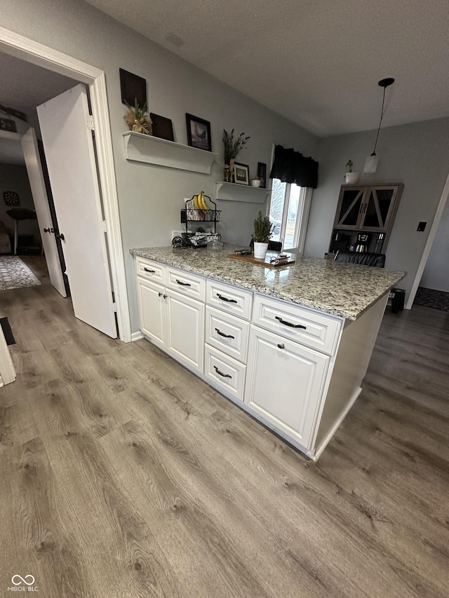 kitchen featuring light stone counters, open shelves, hanging light fixtures, light wood-style floors, and white cabinets