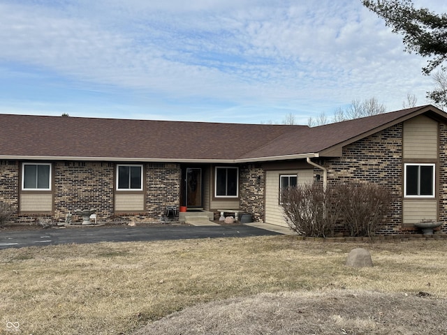 view of front facade featuring entry steps, brick siding, roof with shingles, and a front yard