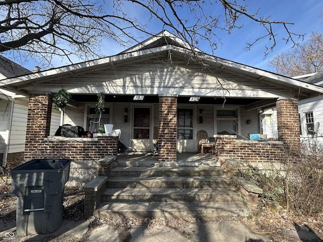 back of house featuring brick siding and covered porch