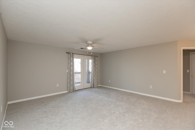 spare room with light carpet, ceiling fan, a textured ceiling, and baseboards