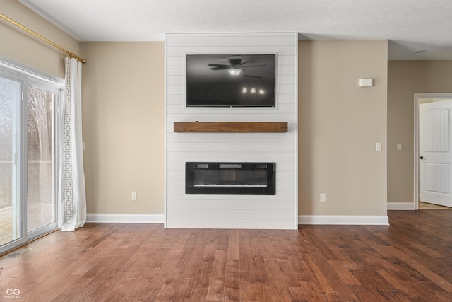 unfurnished living room with a fireplace, wood finished floors, visible vents, and baseboards