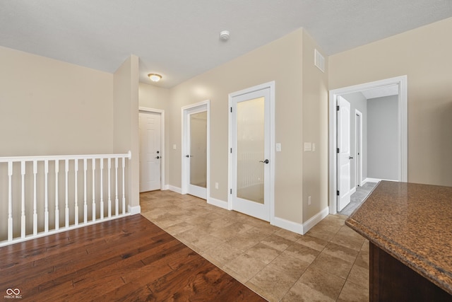 hallway with baseboards, visible vents, and wood finished floors