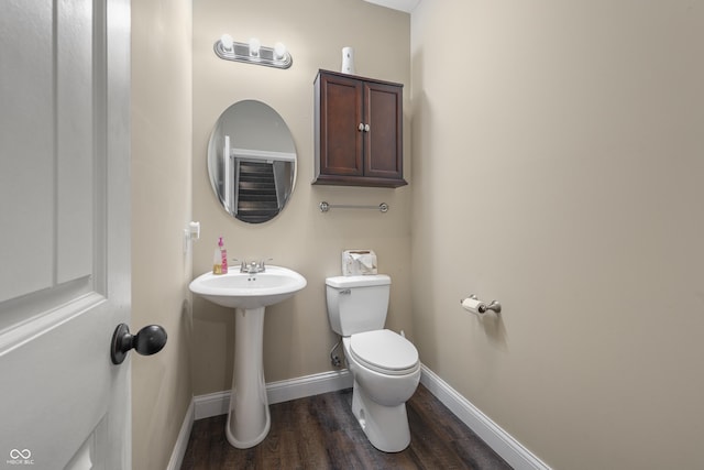 bathroom featuring toilet, a sink, baseboards, and wood finished floors