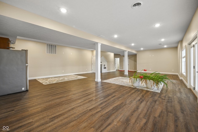 basement with freestanding refrigerator, visible vents, baseboards, and wood finished floors