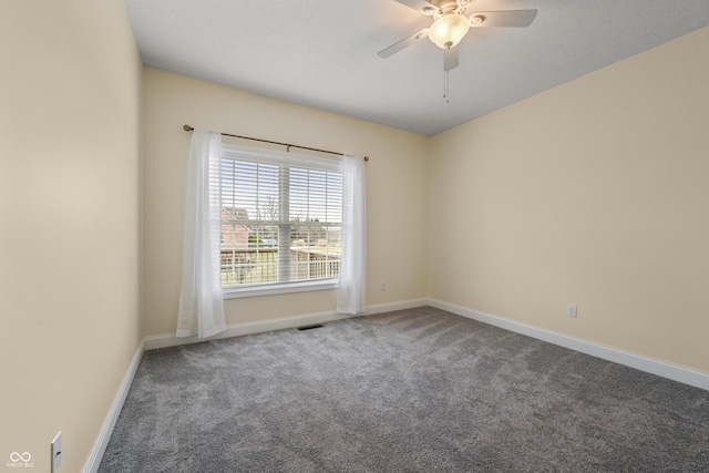 carpeted empty room featuring a ceiling fan, visible vents, and baseboards