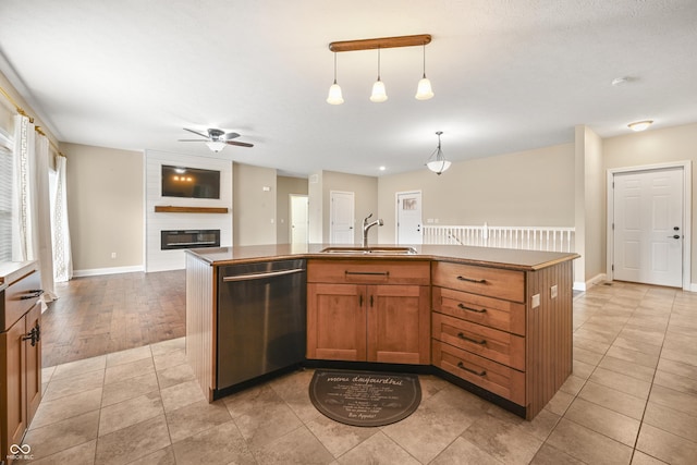 kitchen with a large fireplace, light tile patterned floors, dishwasher, open floor plan, and a sink